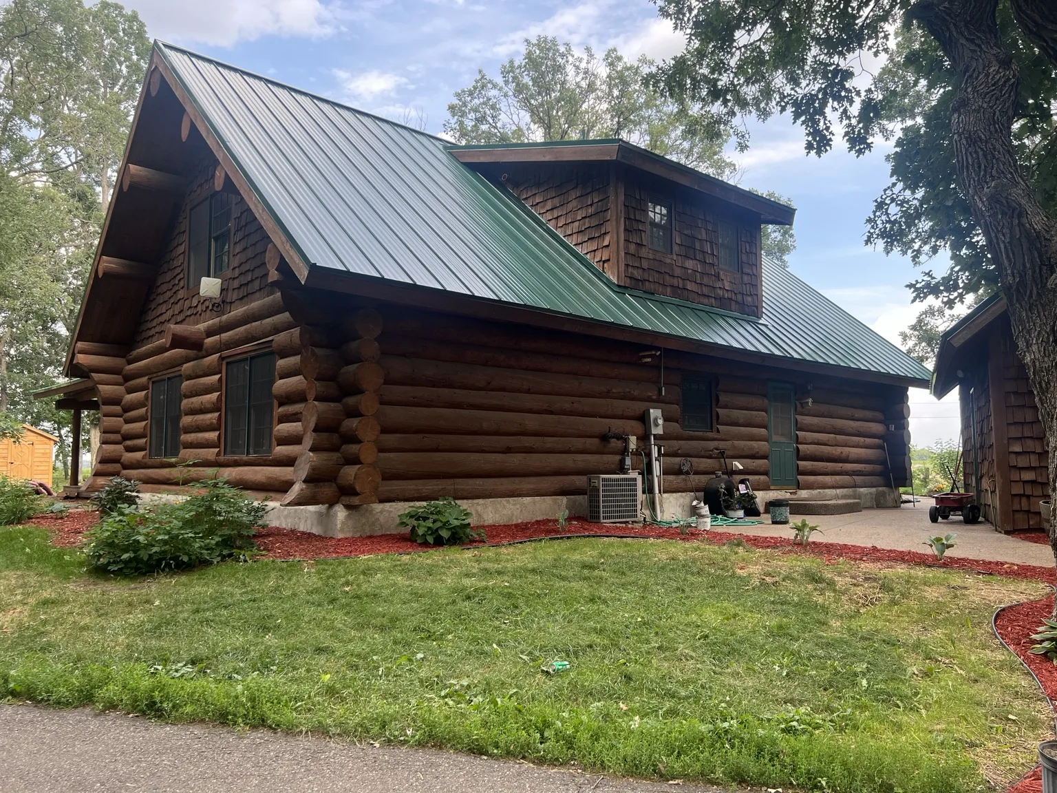 Green metal roof on a log home from a Genesis roofing project