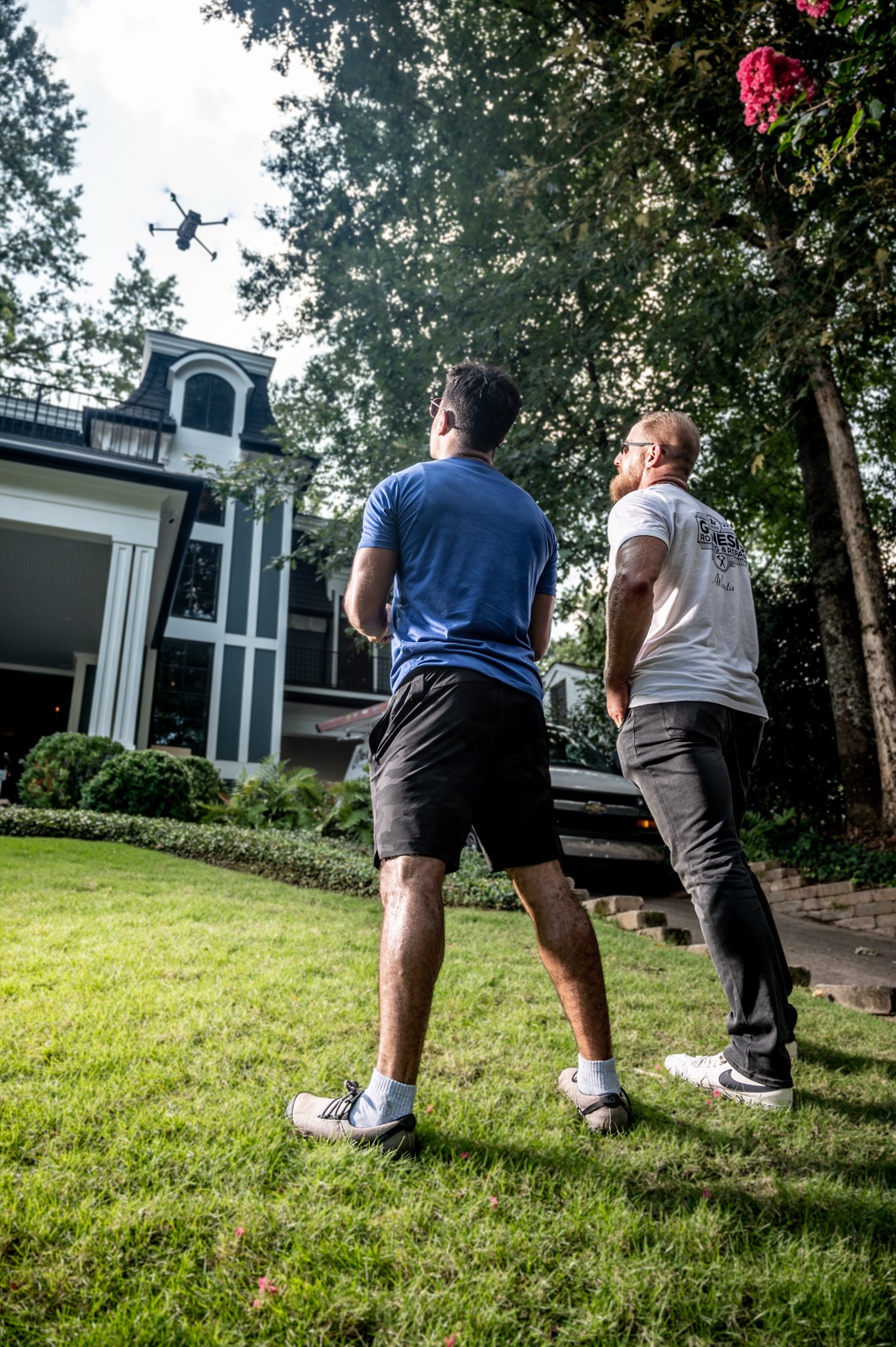 Steven Schmit with another person at a home, with a drone overhead